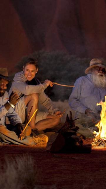 Sitting around a campfire at night | Voyages Indigenous Tourism